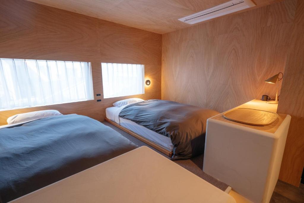 1 dormitorio con 2 camas, mesa y lámpara en APARTMENTS by Bed and Craft, en Inami