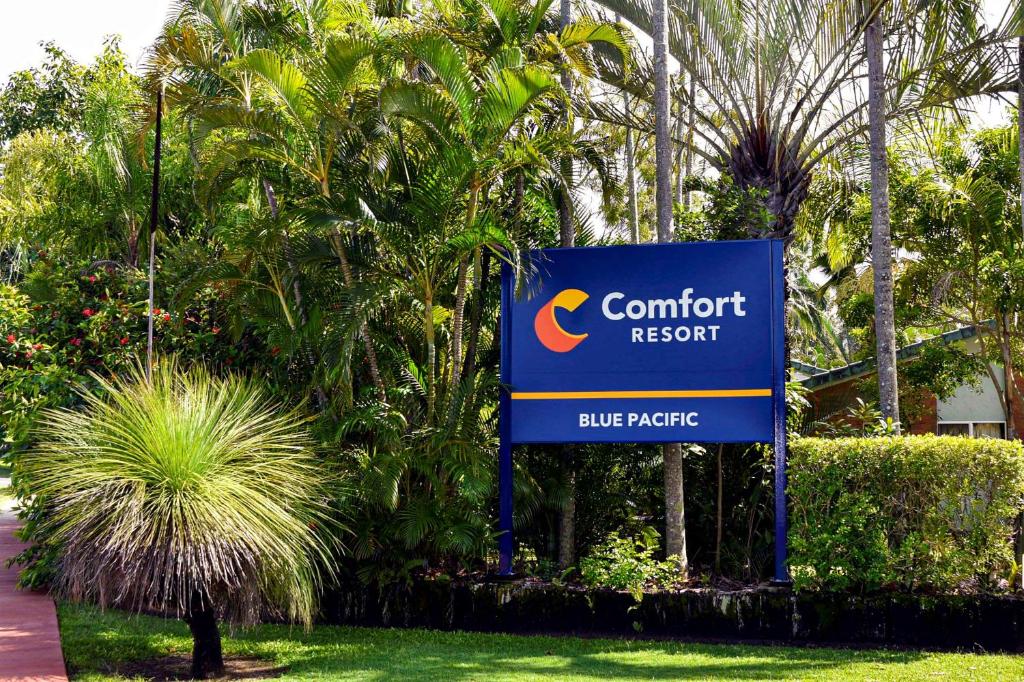 マッカイにあるComfort Resort Blue Pacificの木の前の安楽リゾートの看板