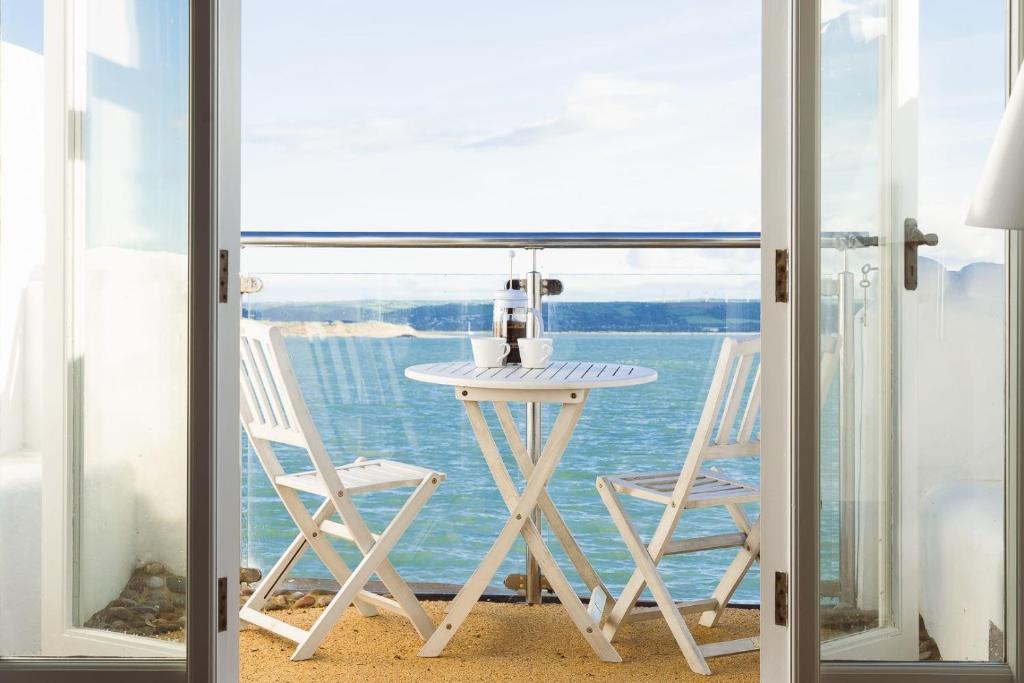 a table and chairs on a balcony with a view of the ocean at Sea View Cottage Dream By The Water in Appledore