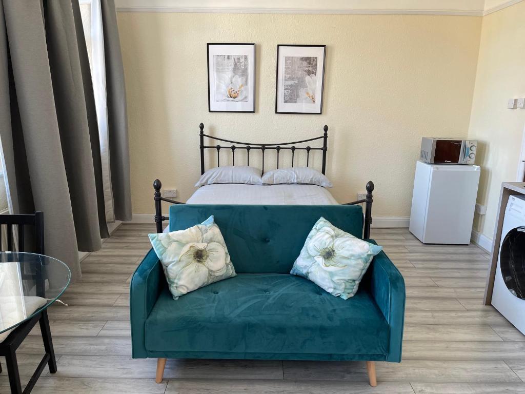 a green couch in a room with a bed at Cosy Studio With Full Facilities. in London