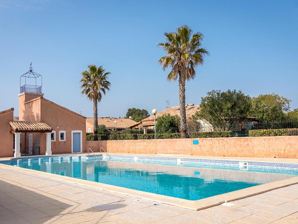 a swimming pool with palm trees in the background at Appartement Loupian, 2 pièces, 4 personnes - FR-1-604-9 in Loupian