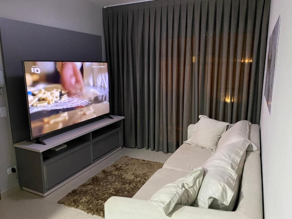 uma sala de estar com um sofá e uma televisão em Apartamento próximo da Lucas em Atibaia