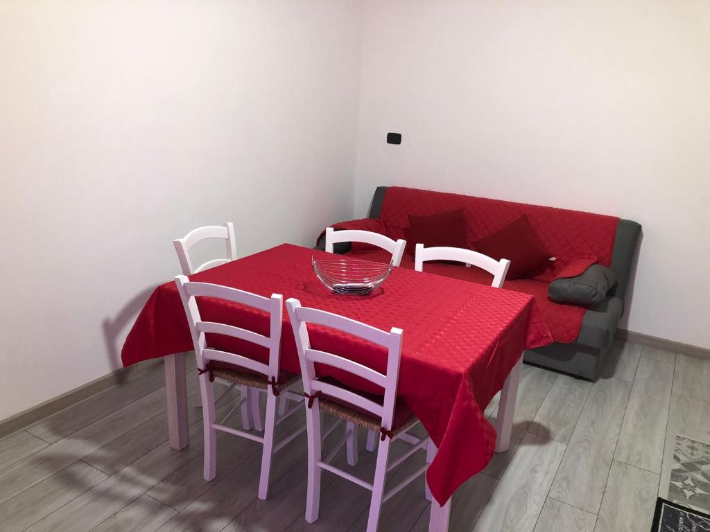 een eettafel met een rood tafelkleed en witte stoelen bij Balai house in Porto Torres
