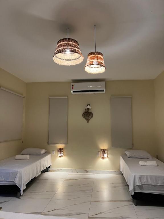 een kamer met 2 bedden en 2 verlichting aan de muur bij Green Village pousada Atins in Atins