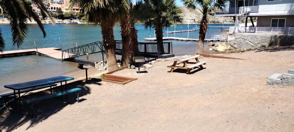 a picnic table and benches on a beach next to the water at Relaxing River Family Retreat in Bullhead City