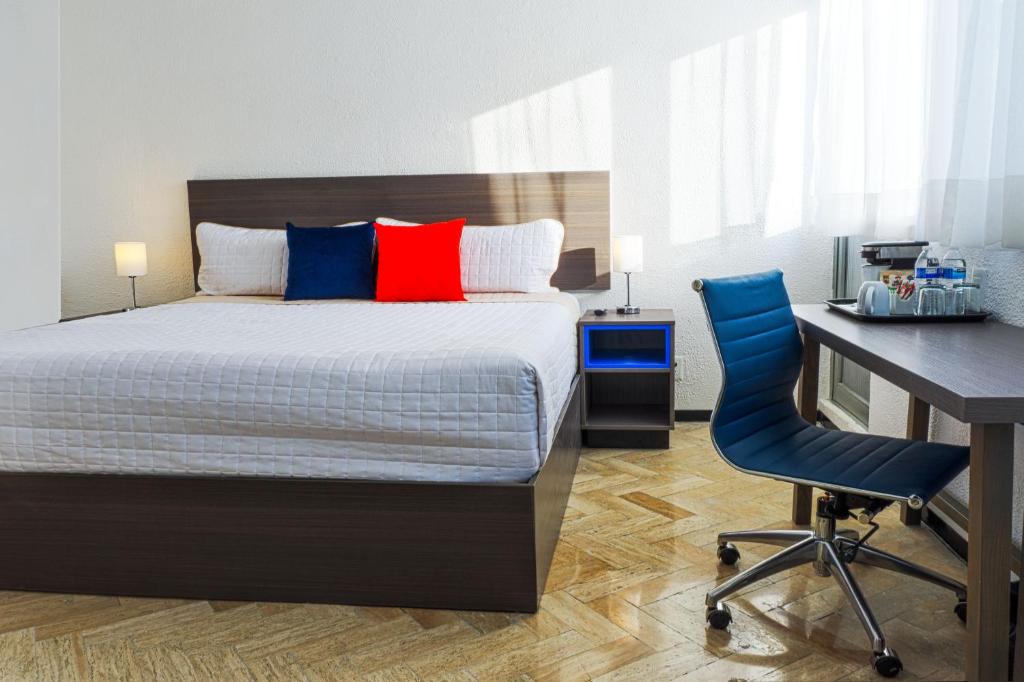 een slaapkamer met een bed, een bureau en een blauwe stoel bij BOK21 - Hotel en Cancun in Cancun