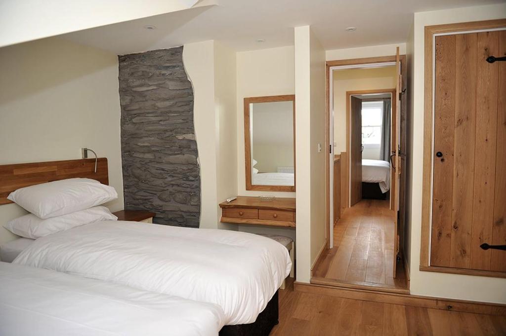 a bedroom with two beds and a stone wall at No 2 The Forge Coniston in Coniston
