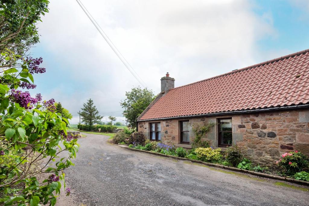 an empty road in front of a stone house at Westwood Cottage in Longniddry