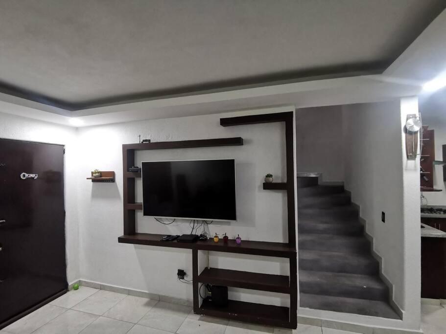 ein Wohnzimmer mit einem TV und einer Treppe in der Unterkunft Villa el roble in Acapulco