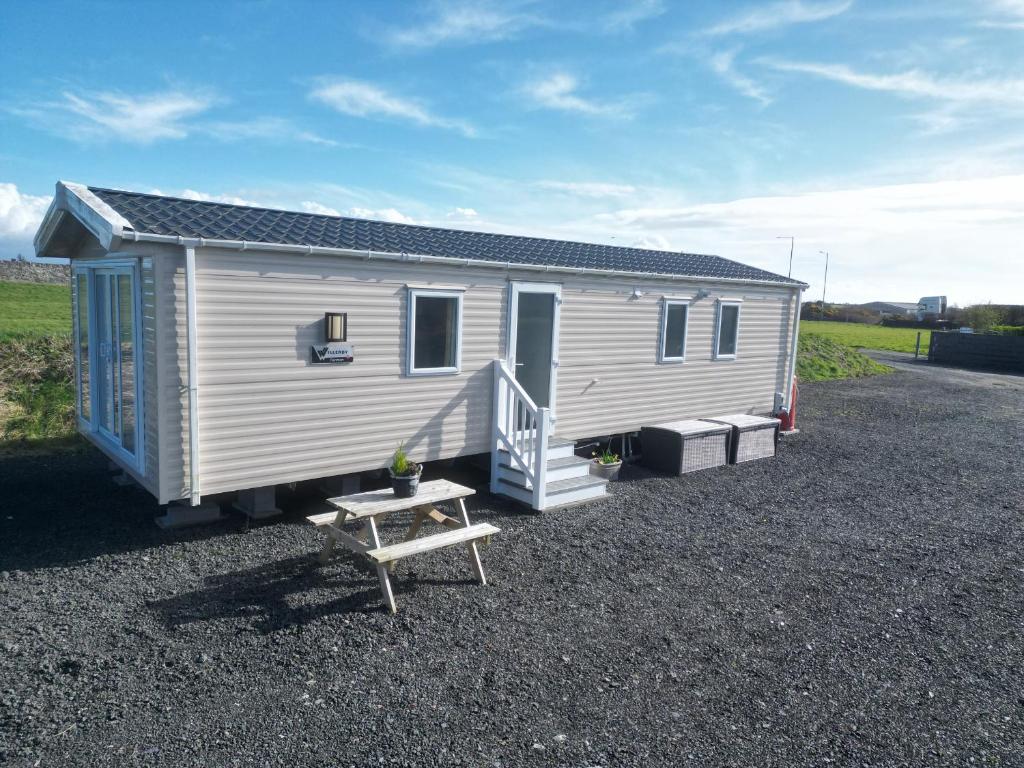 a small white trailer with a bench and a table at Caravan at Boderw in Holyhead