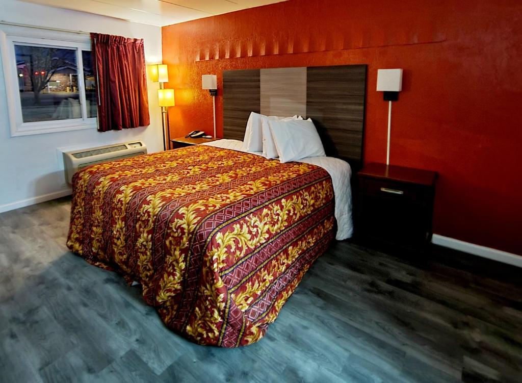 a hotel room with a large bed and a red wall at Budget inn in Vandalia