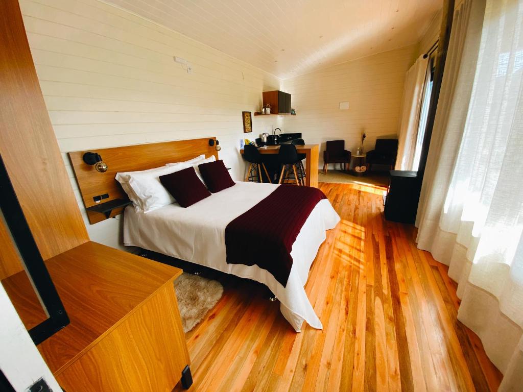 a bedroom with a bed and a desk in it at Refúgio Serra e Flor in Urubici