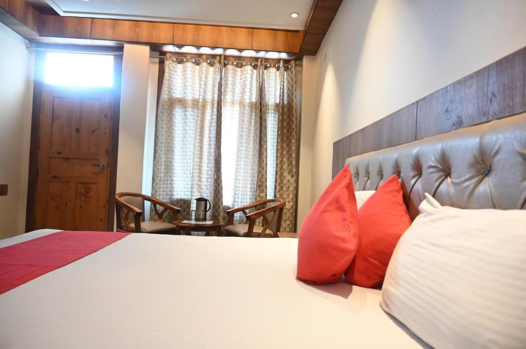1 dormitorio con 1 cama grande con almohadas rojas en Hotel Apple Blossom B$B en Manāli