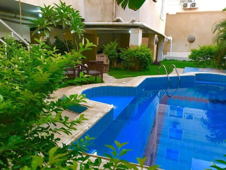 ein blauer Pool in einem Garten mit Pflanzen in der Unterkunft فيلا مبهجة مع مسبح وحديقة رائعة in Madinat as-Sadis min Uktubar