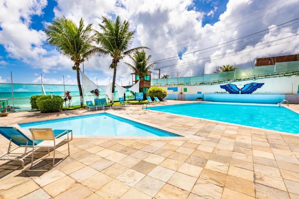 una piscina con palmeras y el océano en Apart Ponta Negra Beach Natal -Lovely Flat, en Natal