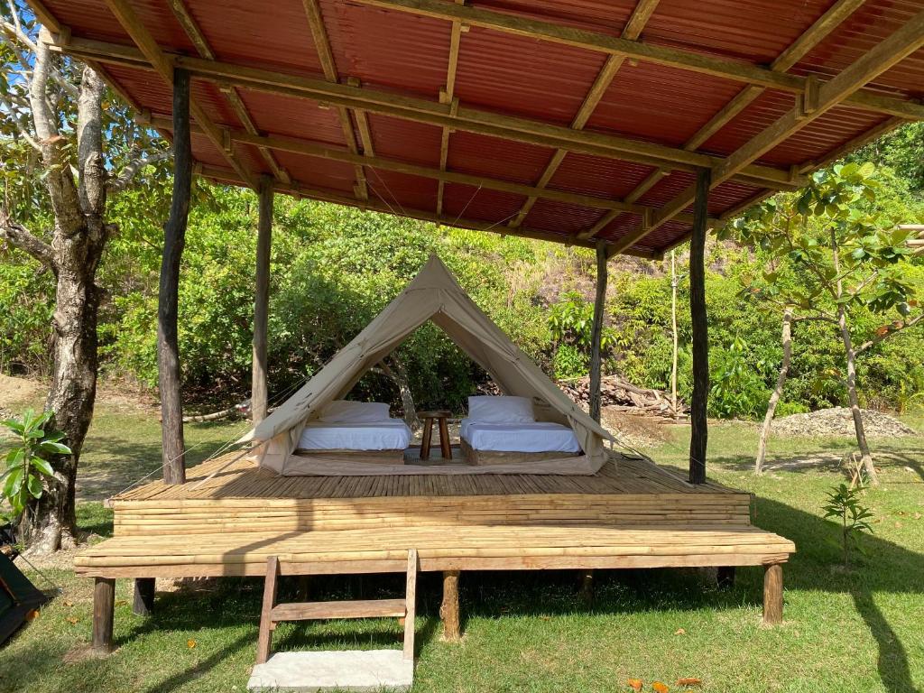 a tent with a table and a wooden deck at CED Farm in El Nido