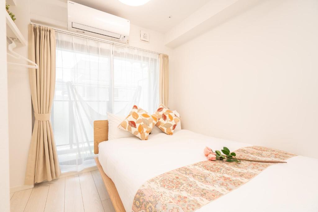 a white bedroom with a bed and a window at リアル大久保　Apartment Hotel in Tokyo