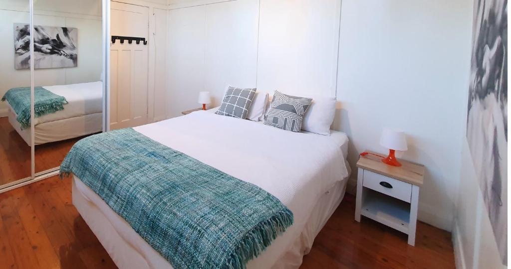 Habitación blanca con cama y espejo en Discover Booker Bay - Central Coast Family Getaway, en Booker Bay