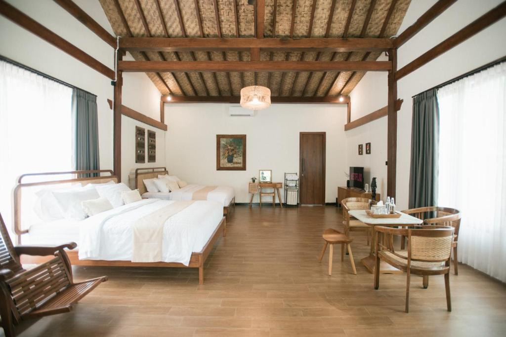1 dormitorio con 1 cama grande, mesa y sillas en LAYANA FARMSTAY en Banyuwangi