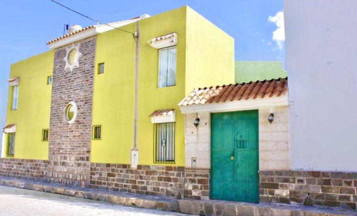 un edificio amarillo con una puerta verde en una calle en Chuklla, en Yanque