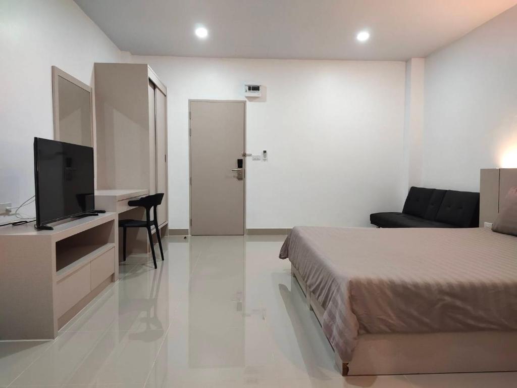 1 dormitorio con 1 cama y escritorio con TV en HADA House Service Apartment, en Bangkok
