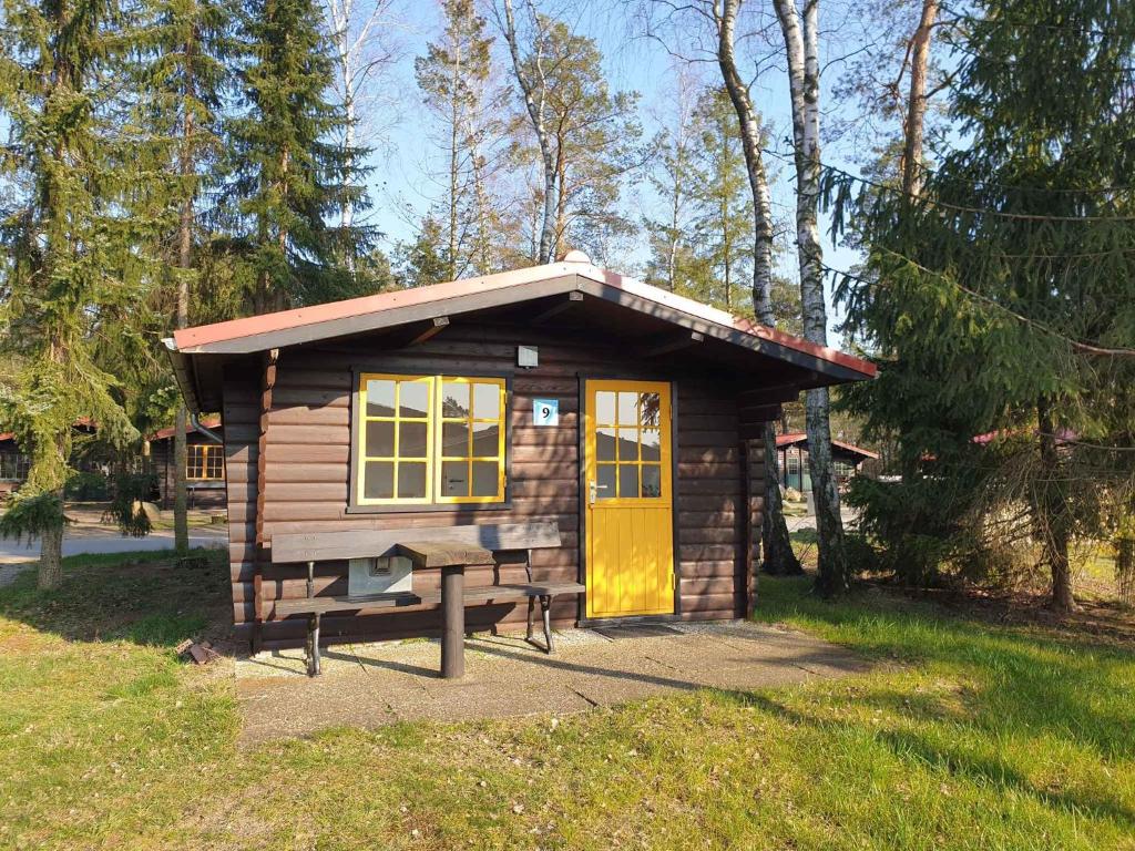 uma pequena cabina com uma porta amarela e um banco em Houses and Apts in Sassenburg Niedersachsen 42038 em Sassenburg