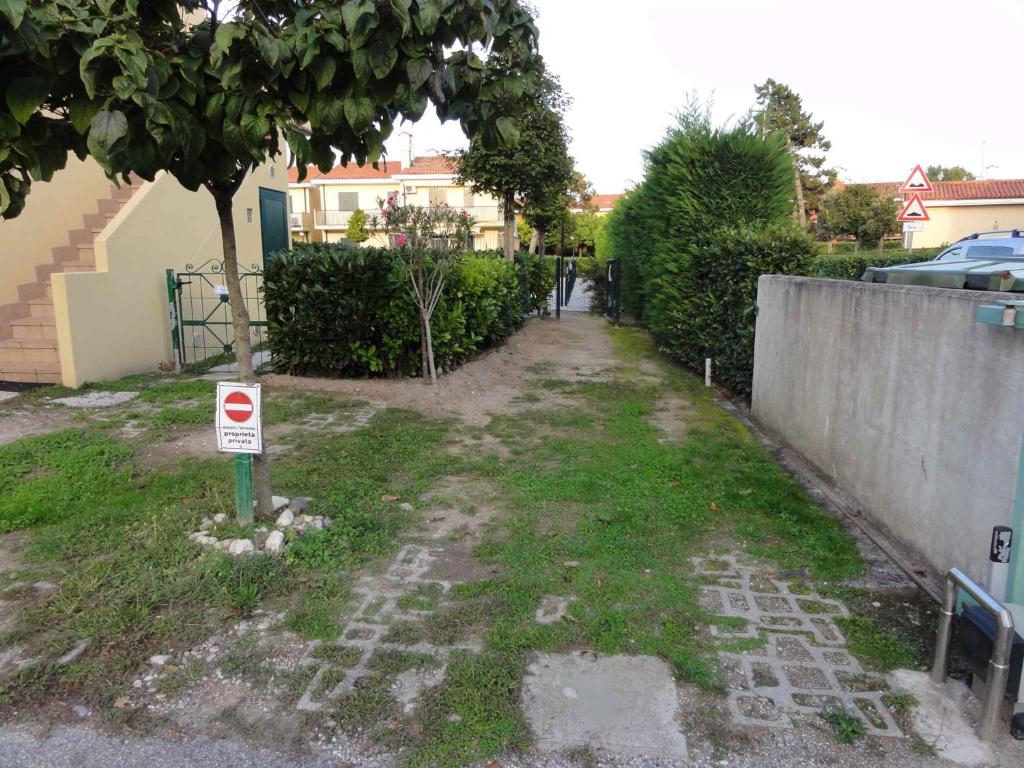 une passerelle dans une cour avec un panneau dans l'herbe dans l'établissement House and Apt in Bibione 38402, à Bibione