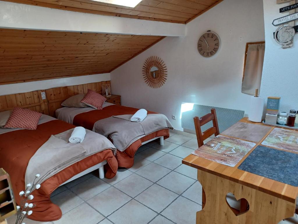 a bedroom with two beds and a table and a clock at STUDIO LE MONT-CENIS, GARAGE pour motards et cyclistes, gare a 800m in Fourneaux