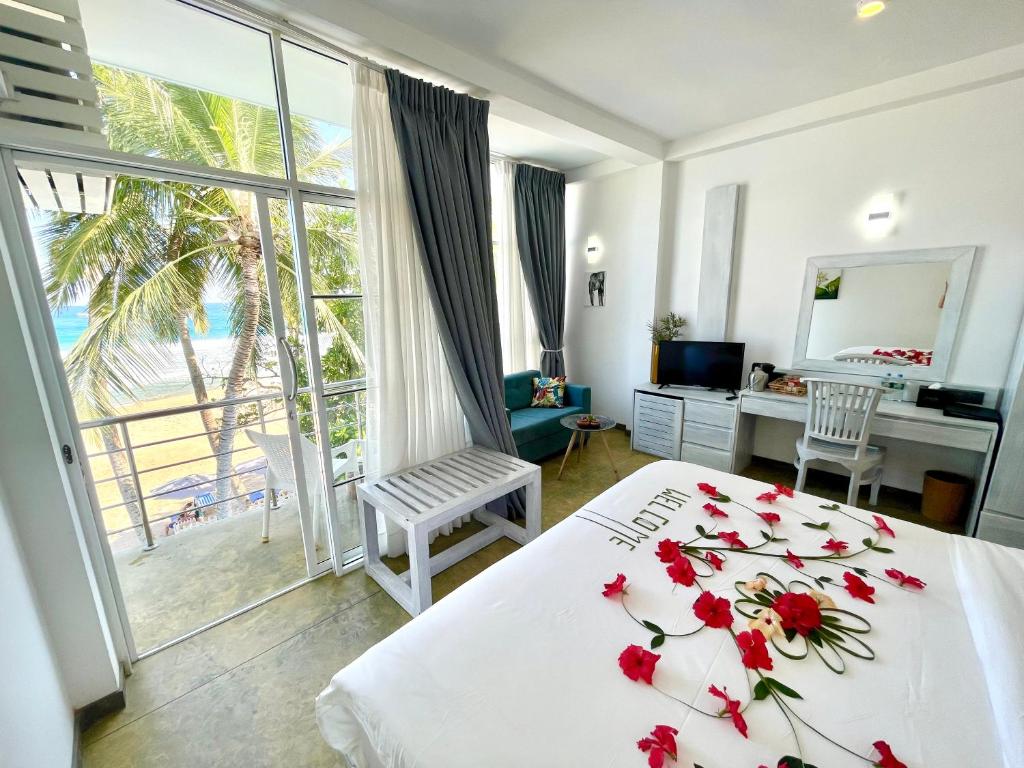 Un dormitorio con una cama con flores rojas. en Smeralda Beach Hotel Dikwella, en Dikwella