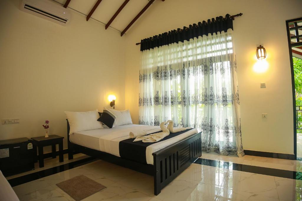 een slaapkamer met een bed en een groot raam bij Riverview Cabana Tissamaharama in Tissamaharama