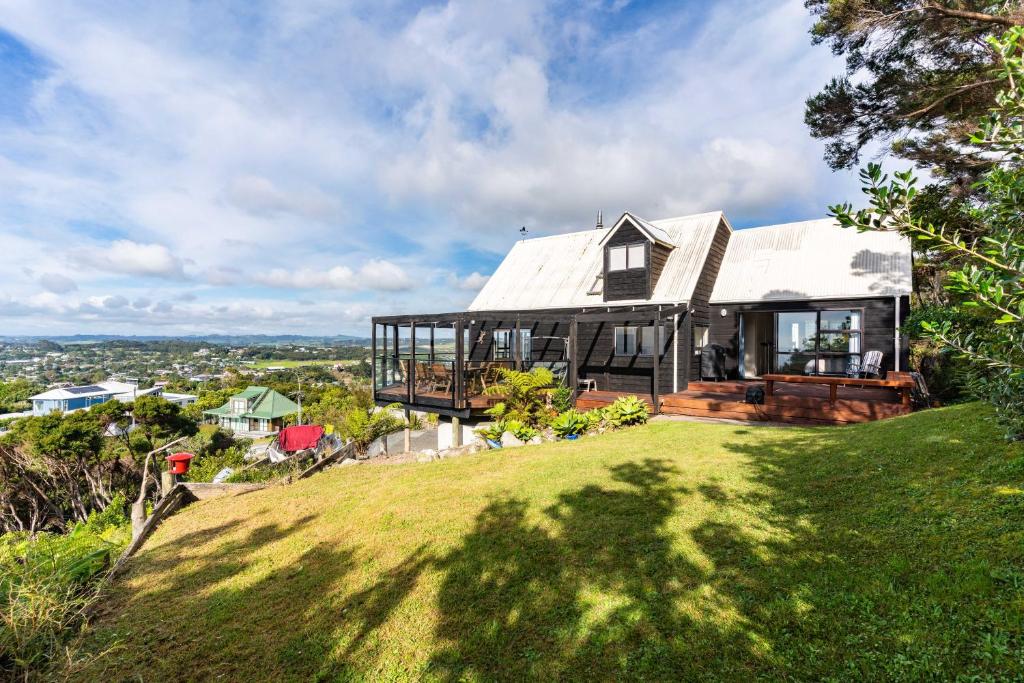 uma casa no topo de uma colina relvada em Simply Fabulous - Mangawhai Heads Holiday Home em Mangawhai