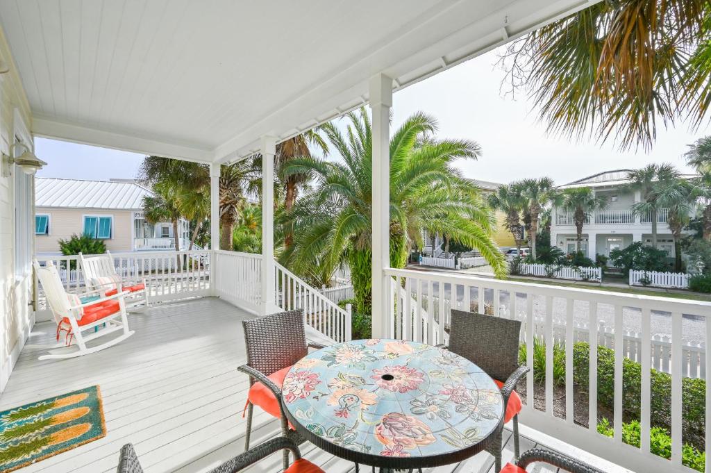 a porch with a table and chairs and palm trees at Shore Fun At Destin Pointe Resort in Destin
