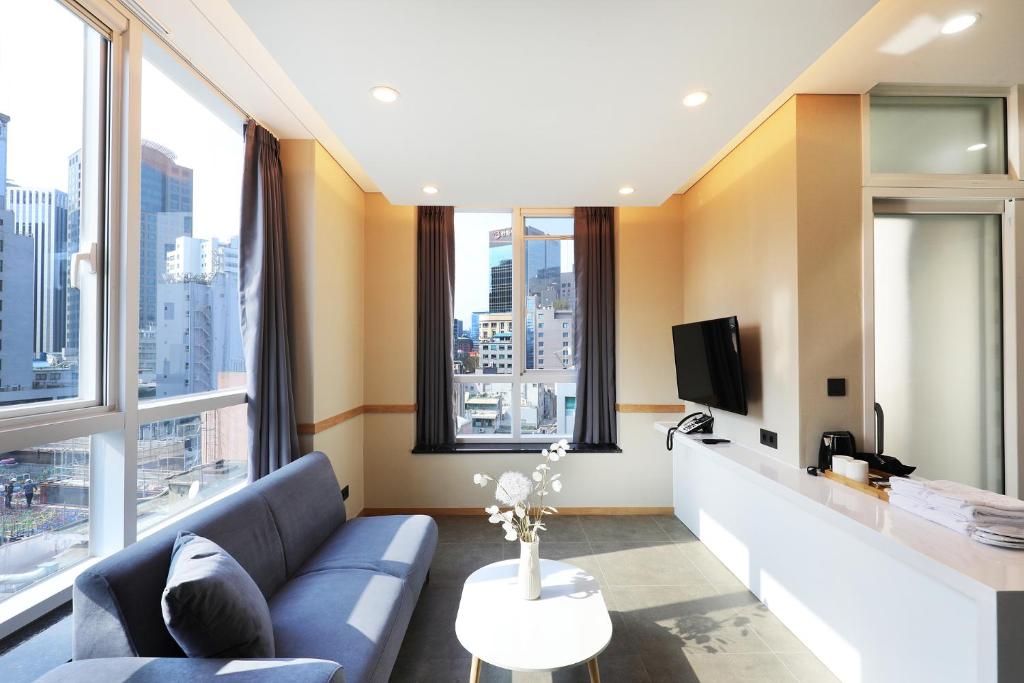ソウルにあるThe Stay Classic Hotel Myeongdongのリビングルーム(青いソファ、大きな窓付)