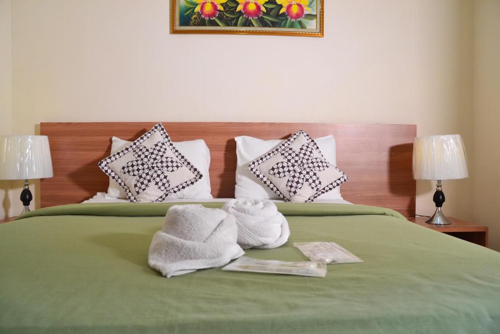 a green bed with towels and pillows on it at Roemah Canting Homestay in Yogyakarta