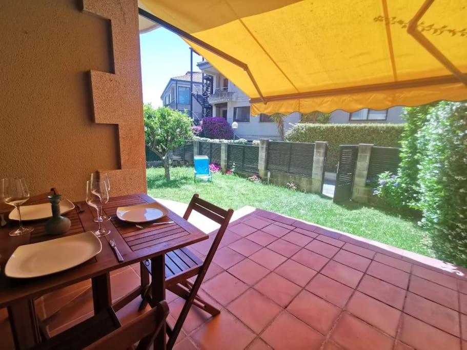 a wooden table with chairs and an umbrella on a patio at P° Olmos, Panxón, bajo con jardín privado in Nigrán