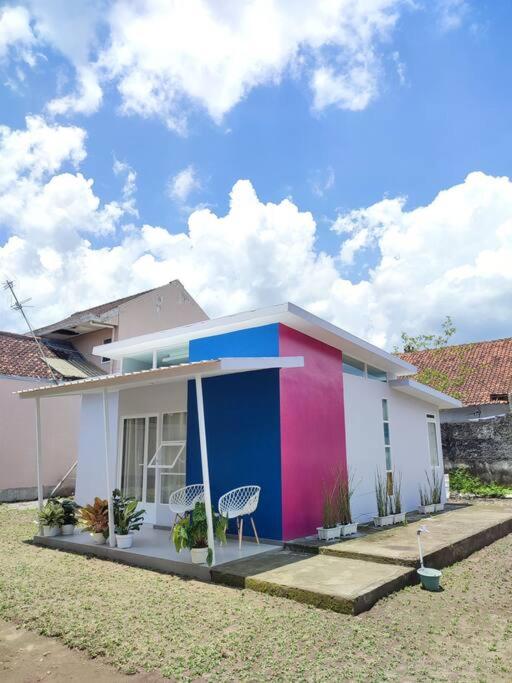 a colorful house with two chairs in front of it at Kembang Homestay Yogyakarta in Seturan