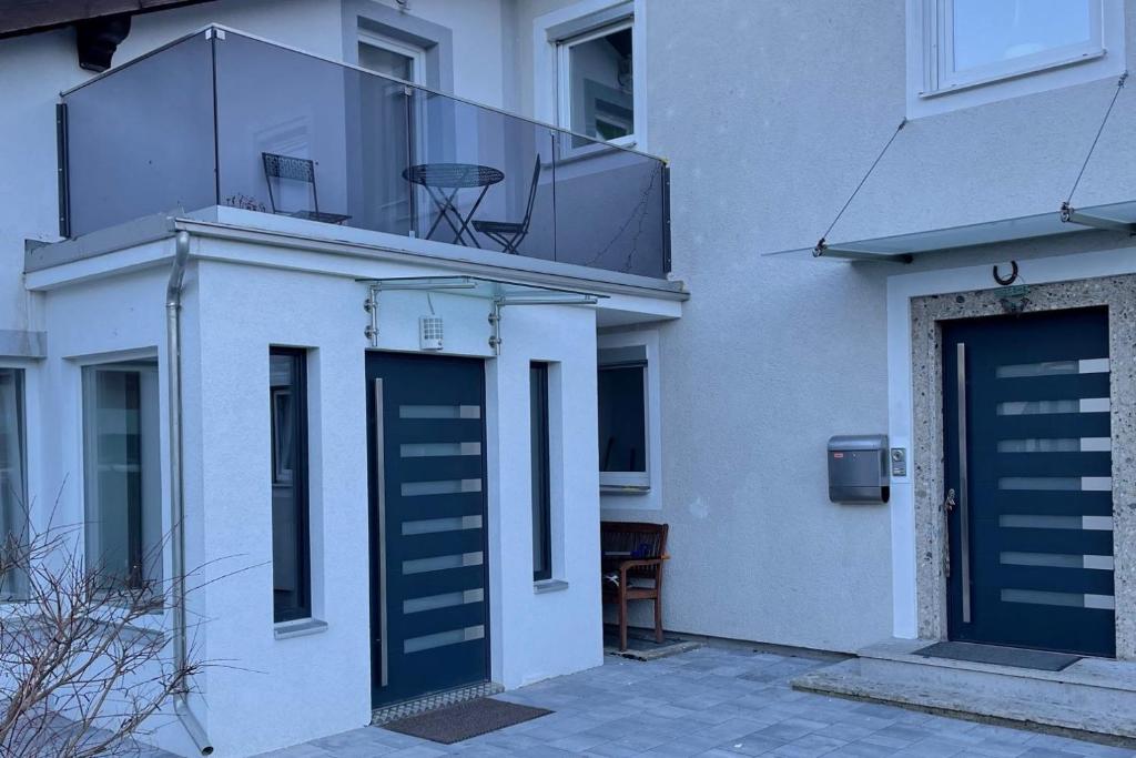 a white building with a blue door and a balcony at Ferienwohnung Bullaku in Piding