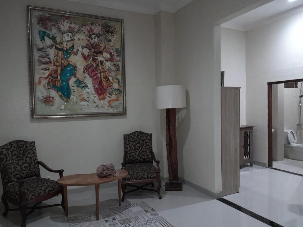 a living room with a table and two chairs and a painting at Djembar Inn in Kalasan