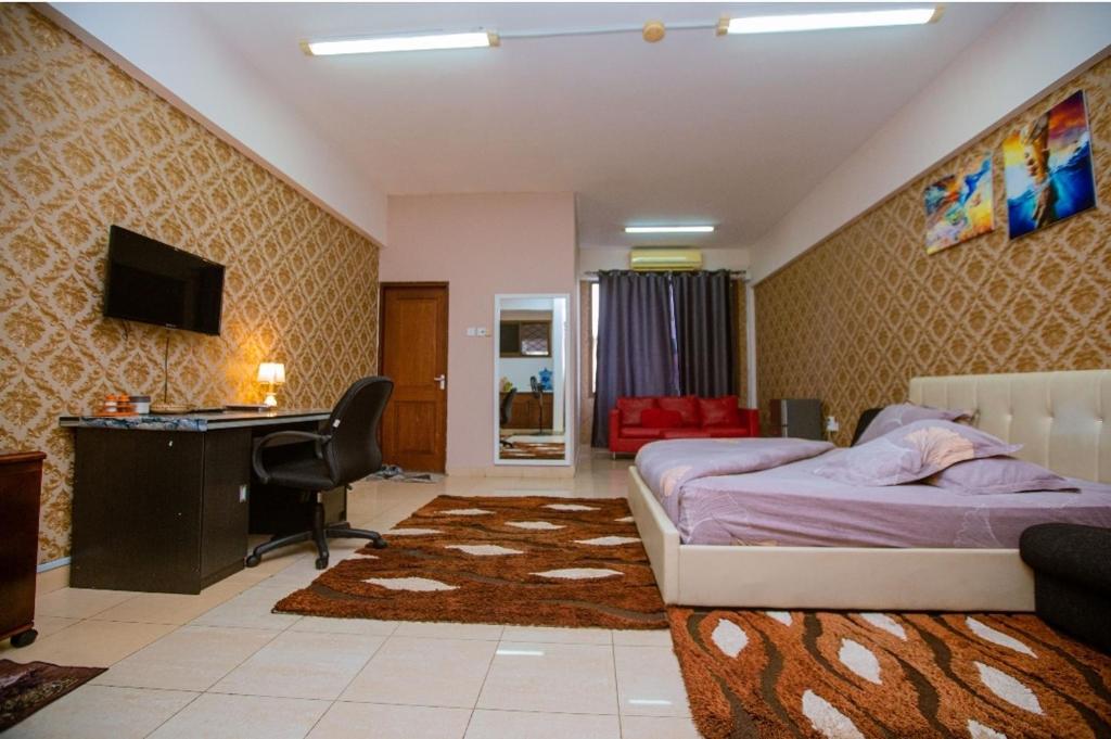 a bedroom with a bed and a desk and a desk at Queens Rentals - Studio Apartments - Village Walkway - Masaki - Dar es Salaam in Dar es Salaam