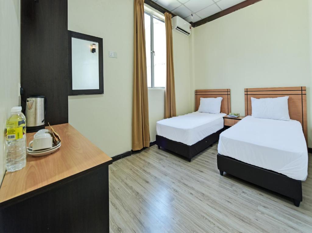 Capital O 90761 D Jiwa Hotel في Pendang: غرفة في الفندق بسريرين ومكتب يوجد به هاتف