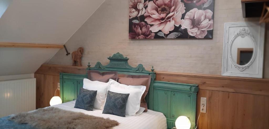 a bedroom with a bed with a green headboard and pillows at De Blauwe Maaten in Neerglabbeek