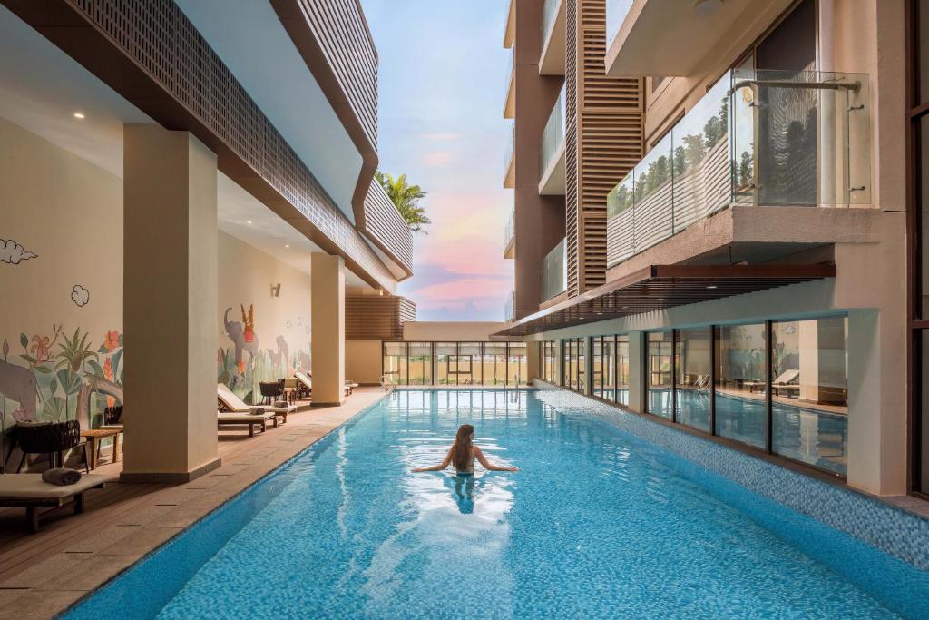a girl swimming in a swimming pool in a building at Oakwood Premier Phnom Penh in Phnom Penh