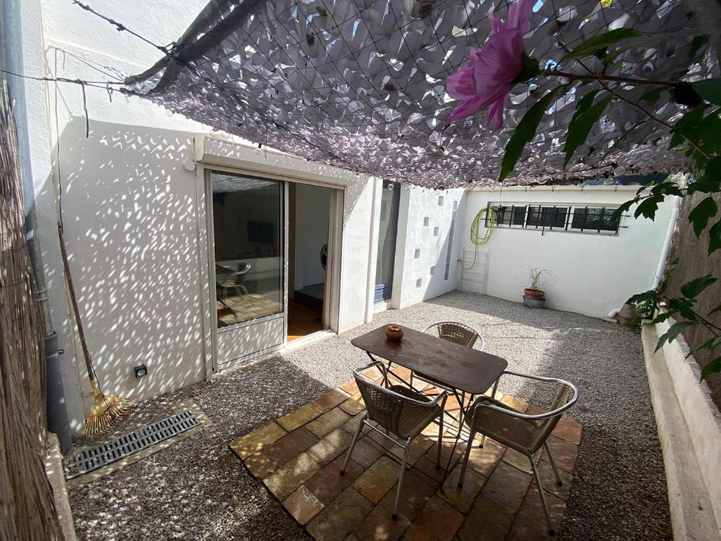eine Terrasse mit einem Tisch, Stühlen und einer lila Blume in der Unterkunft Grand studio de 38m2 et cour indépendante de 25m2 dont wifi et Netflix in Montpellier
