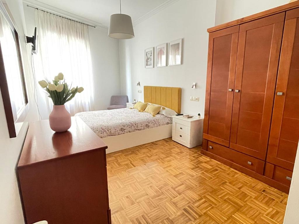 - une chambre avec un lit et un vase de fleurs sur une commode dans l'établissement Apartamento Rey Daviña, à Vilagarcía de Arousa