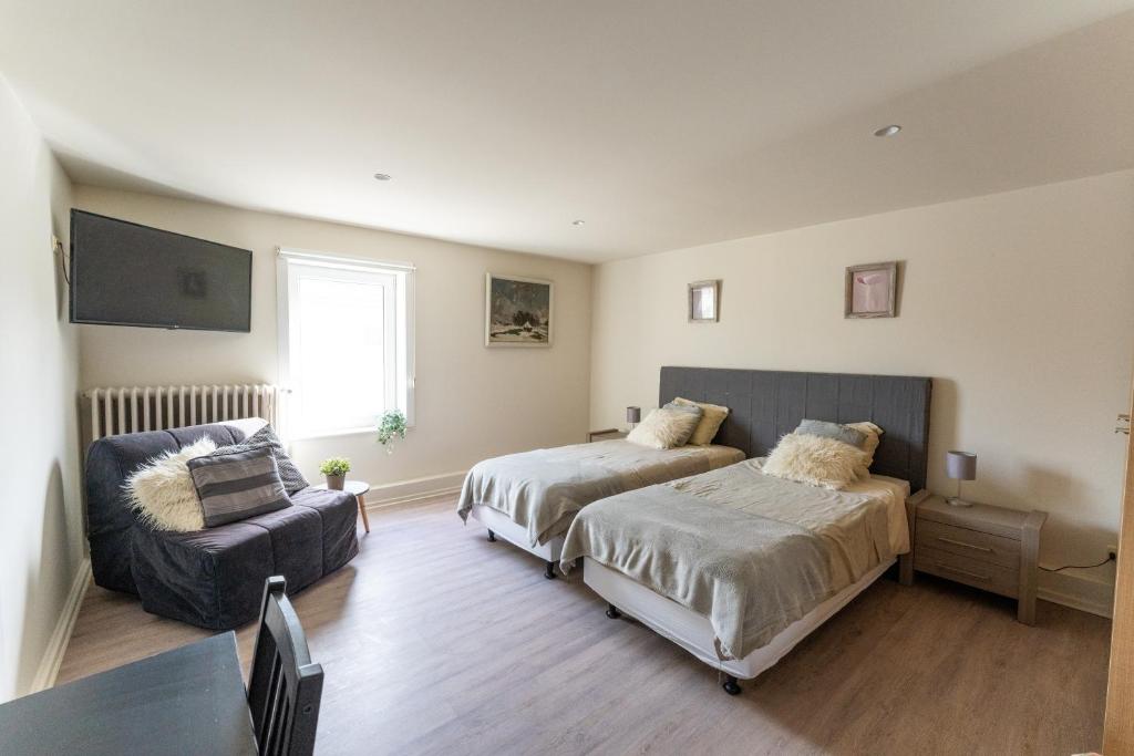 um quarto com 2 camas, um sofá e uma cadeira em B&B Lanterfanters' em Nieuwpoort