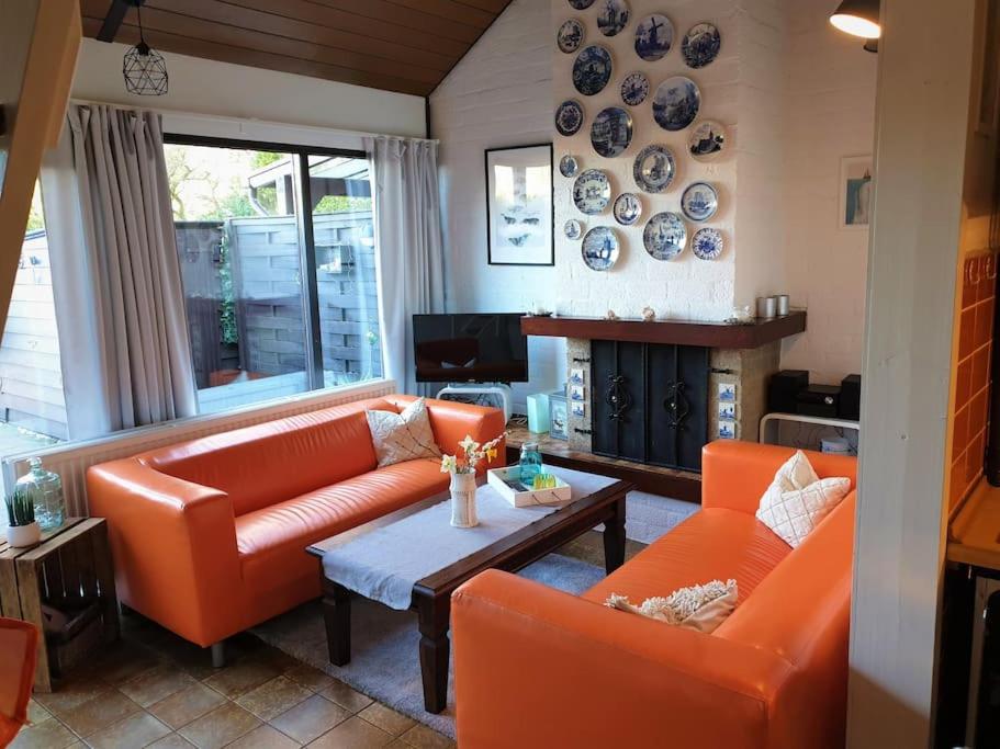 un soggiorno con mobili arancioni e camino di Welkom in DeKreek V59, dem freundlichen Ferienhaus a Bruinisse