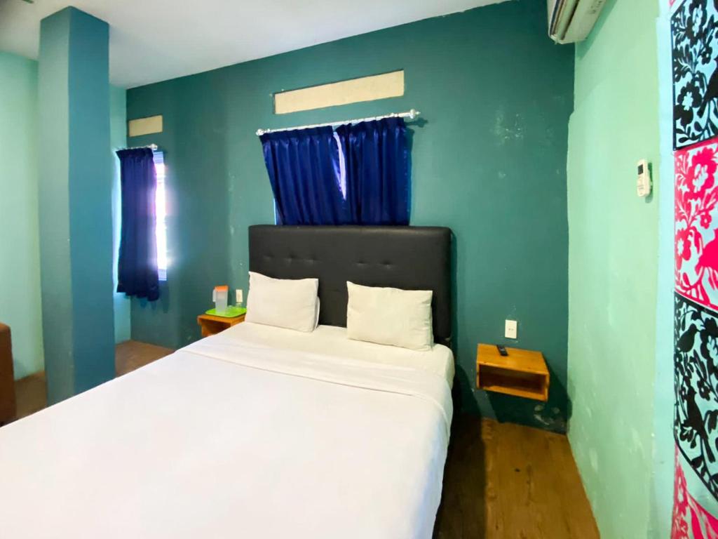 sypialnia z dużym białym łóżkiem z niebieskimi ścianami w obiekcie Sentosa Jaya Guest House near RS Hermina Medan RedPartner w mieście Medan