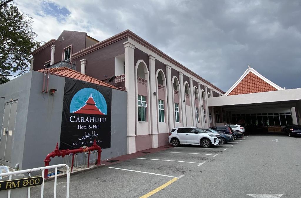 Capital O 90756 Cara Hulu Hotel في Kampong Morten: مبنى فيه سيارات متوقفة في موقف للسيارات