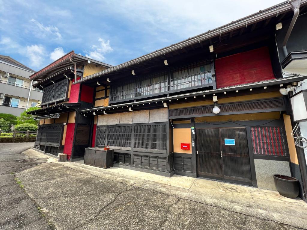 a building with windows and doors on a street at Hostel Murasaki Ryokan in Takayama