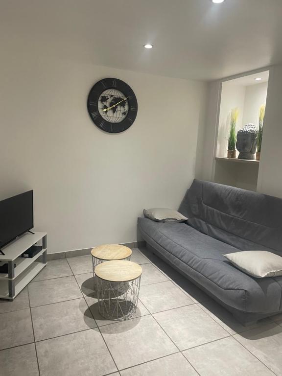 阿格德角appartement Cap d’Agde的客厅里有一张沙发，墙上挂着一只钟